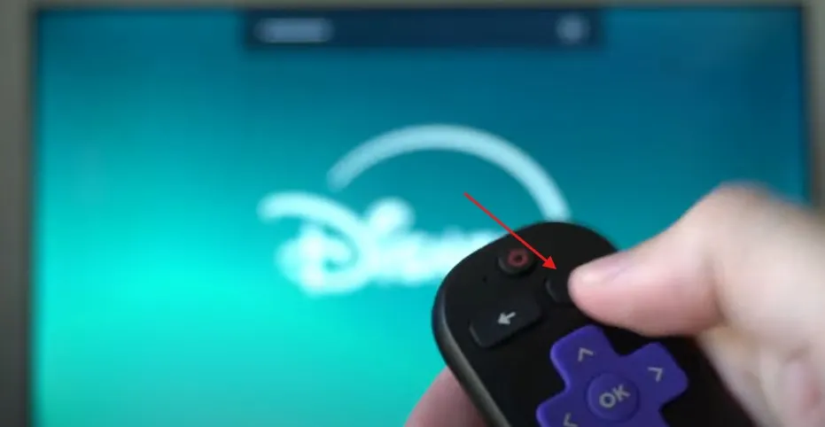 Hand pressing Home button on Roku remote.